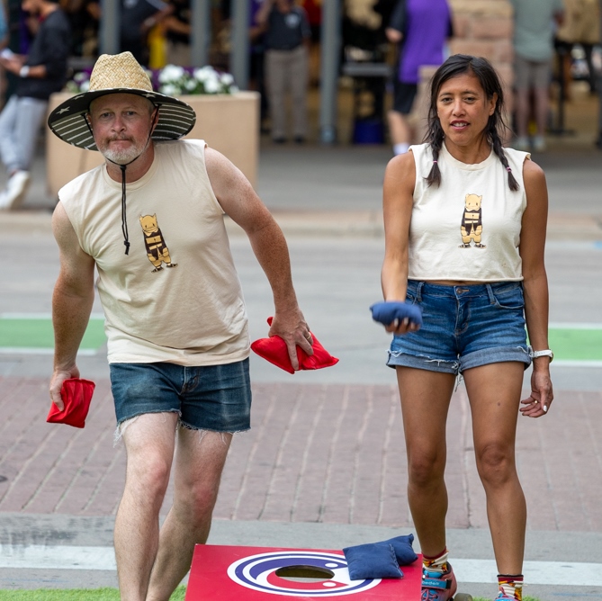 Players tossing bean bags during the Ballpark District cornhole tournament